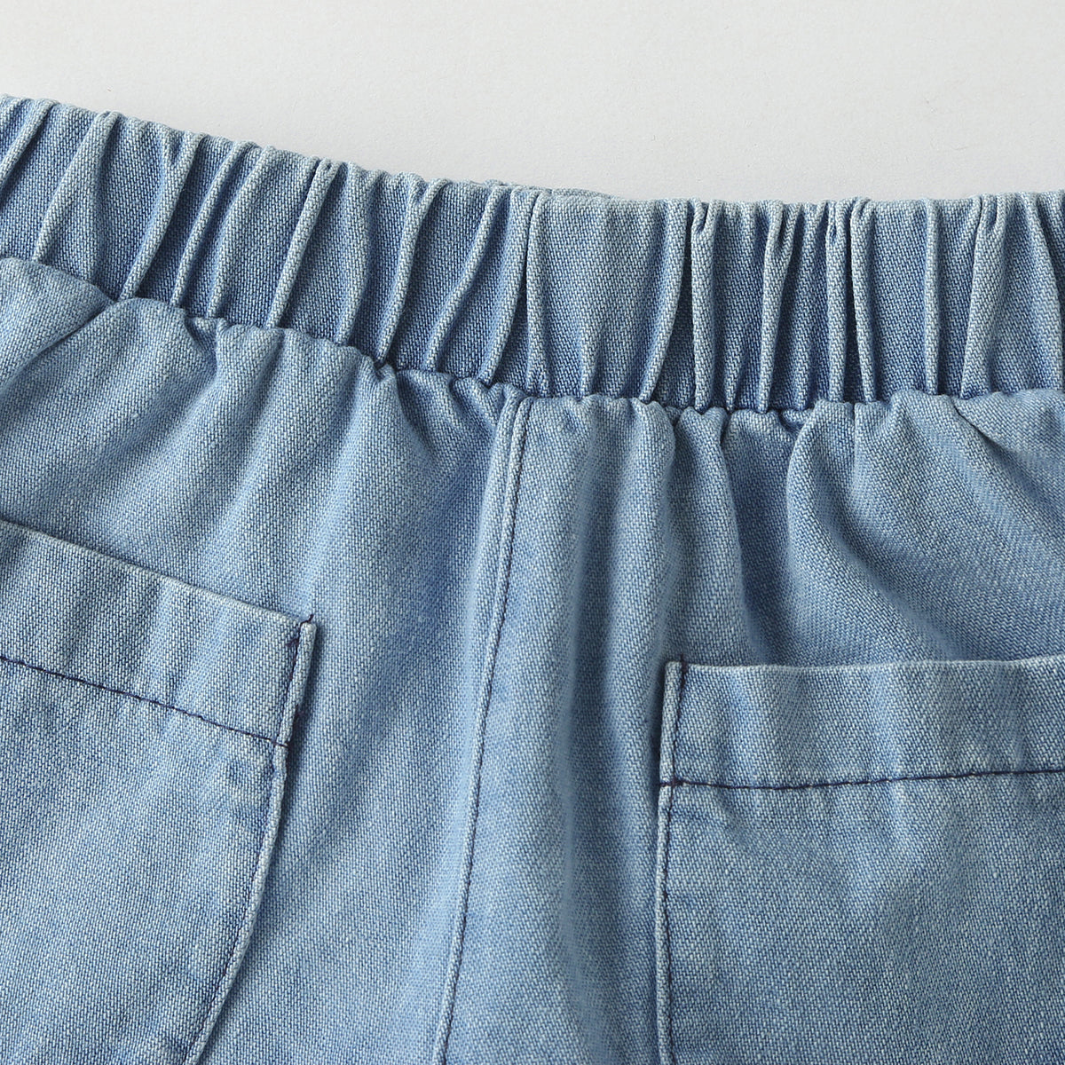 Baby wearing a solid color button front denim shirt and shorts set in blue, perfect for summer outings.