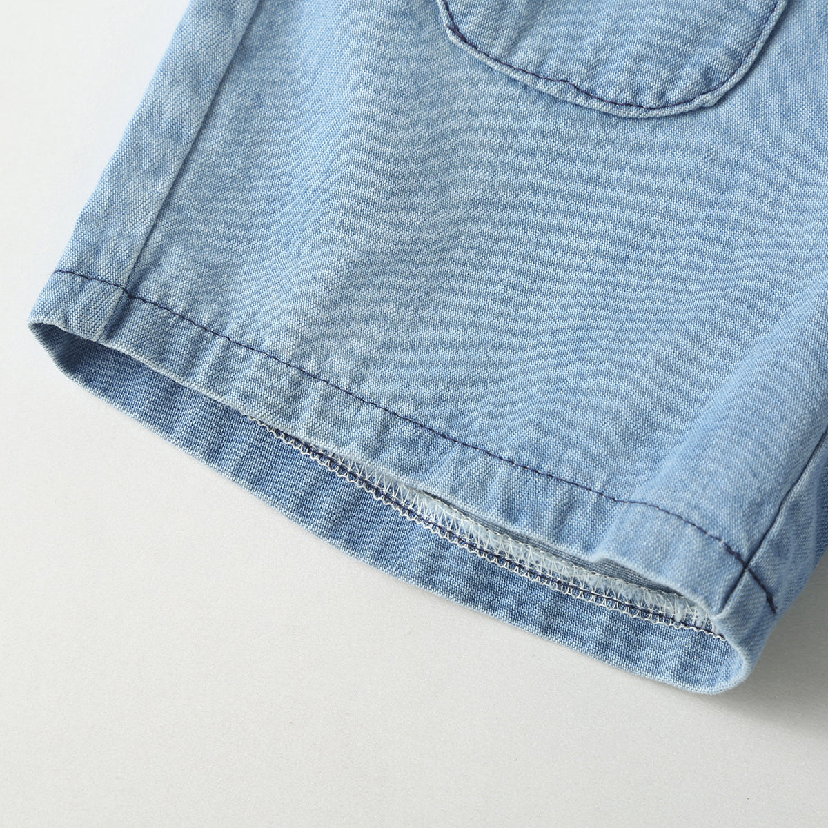 Baby wearing a solid color button front denim shirt and shorts set in blue, perfect for summer outings.