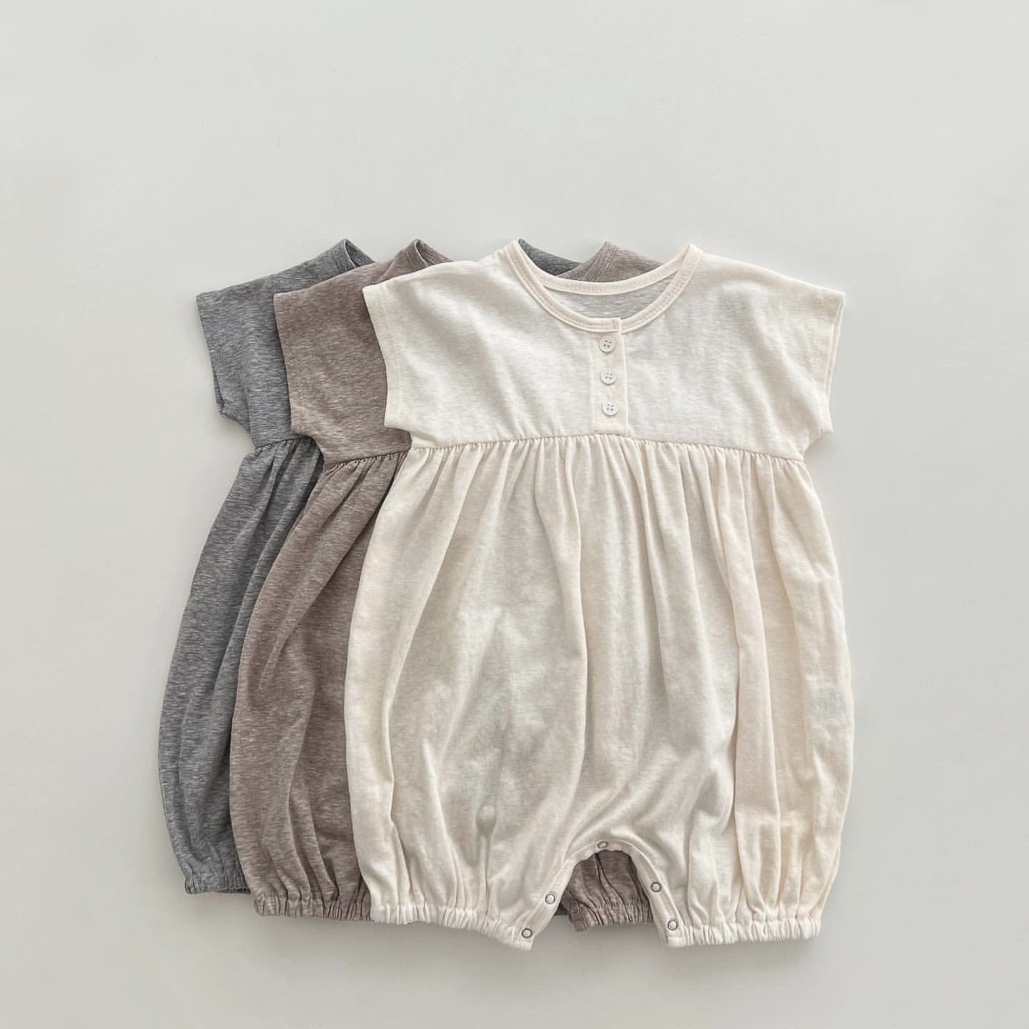 A baby wearing a solid color casual short sleeve romper in apricot, showcasing comfort and style.