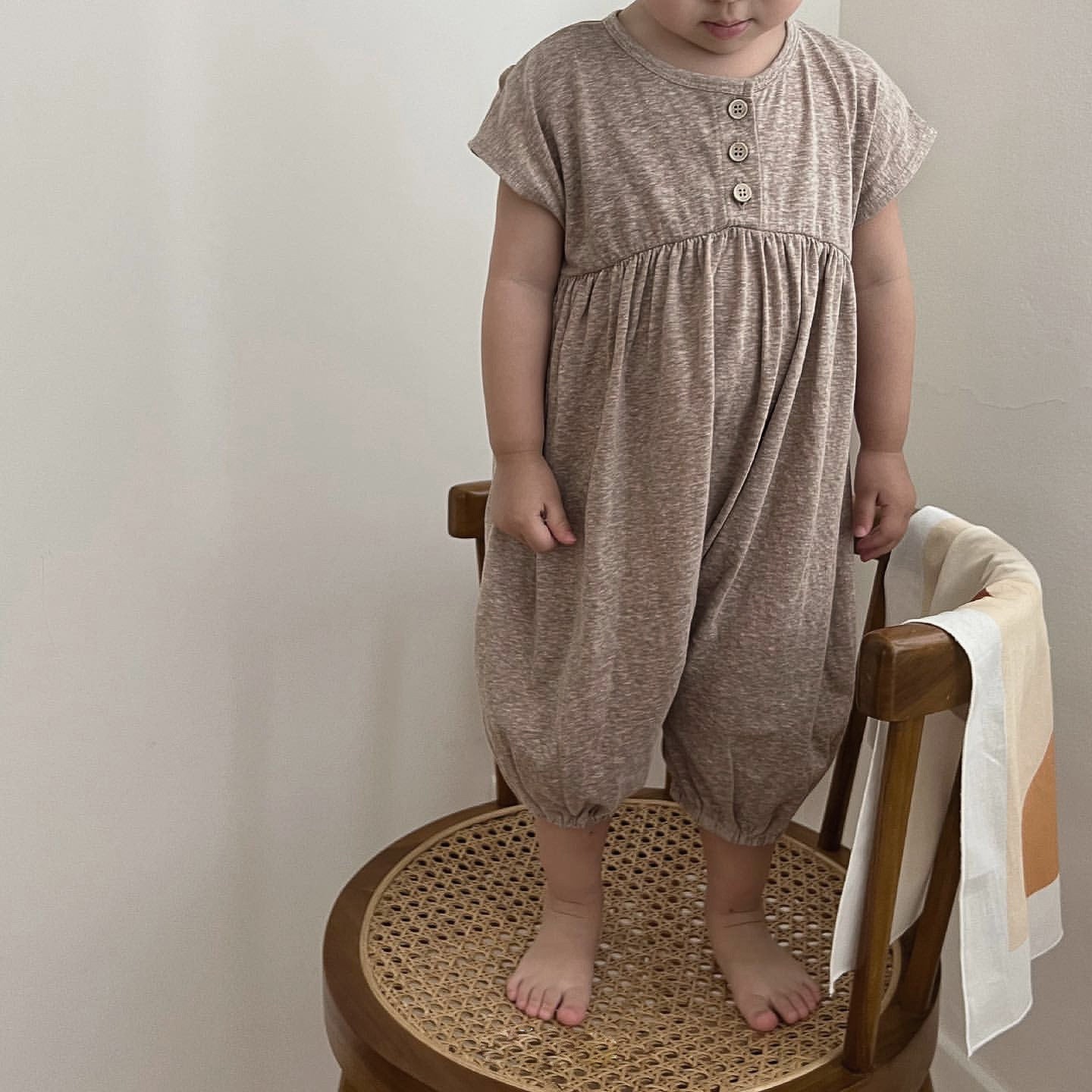 A baby wearing a solid color casual short sleeve romper in apricot, showcasing comfort and style.
