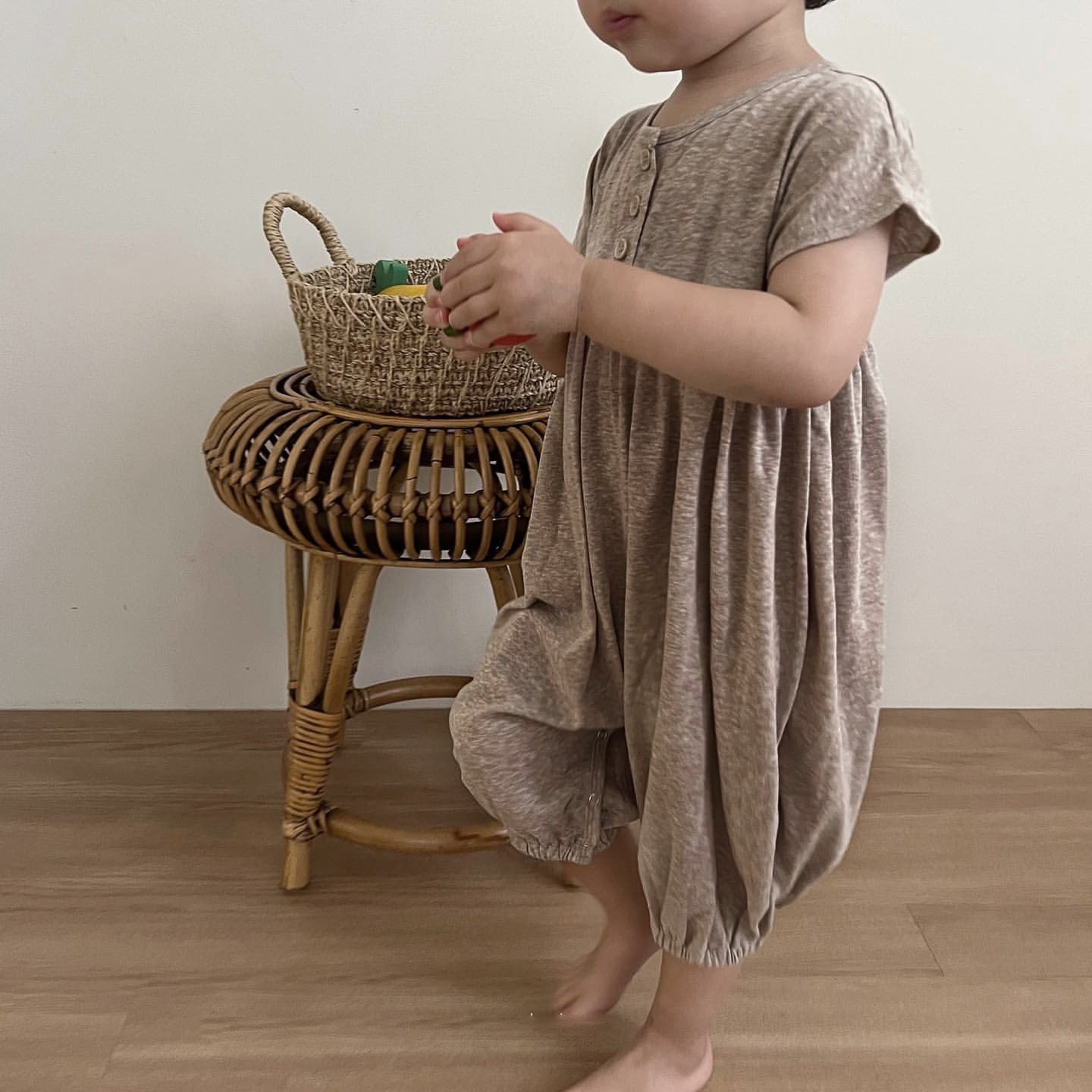 A baby wearing a solid color casual short sleeve romper in apricot, showcasing comfort and style.