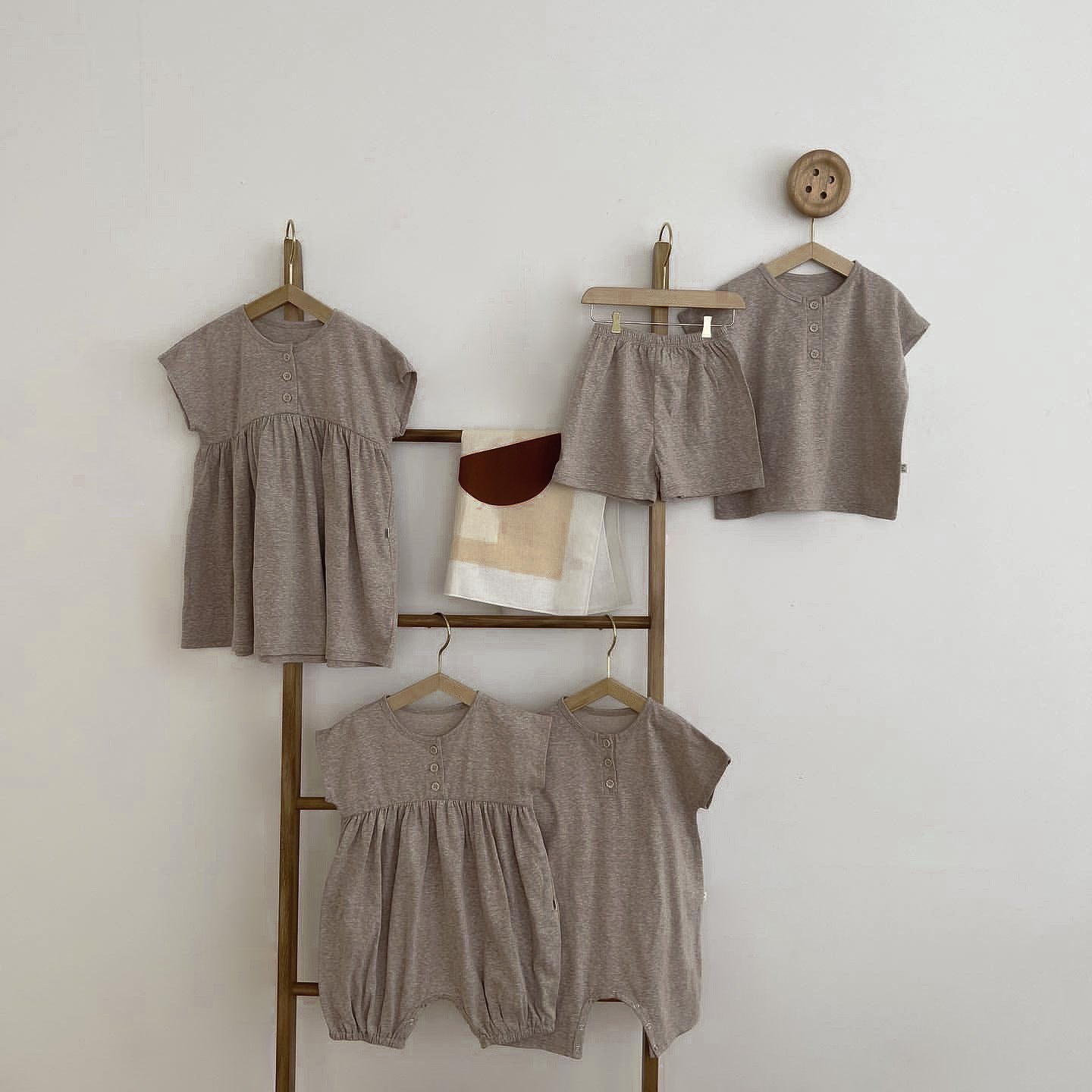 A baby wearing a solid color casual short sleeve romper in apricot, showcasing comfort and style.
