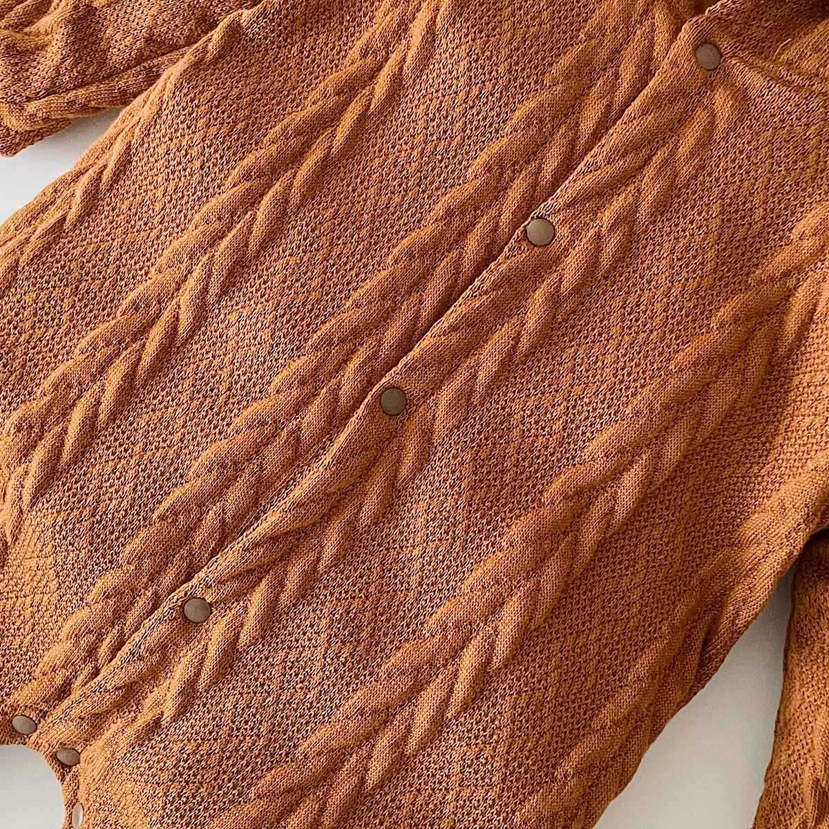 A cozy baby romper featuring a solid crochet-knitted pattern in white and brown, perfect for both baby girls and boys.