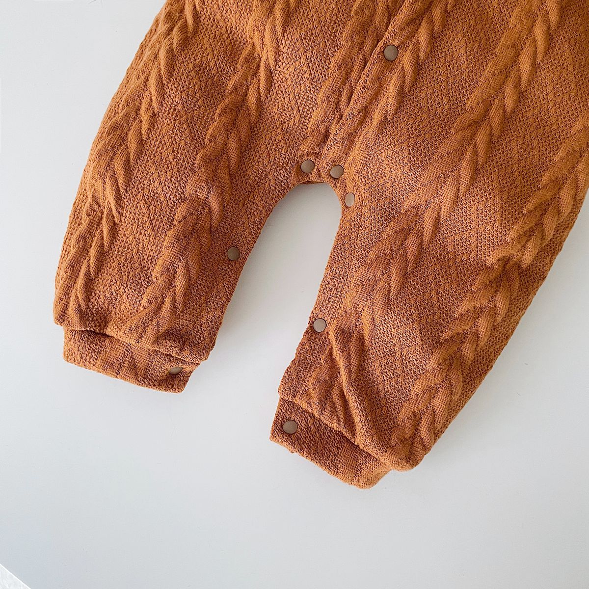 A cozy baby romper featuring a solid crochet-knitted pattern in white and brown, perfect for both baby girls and boys.