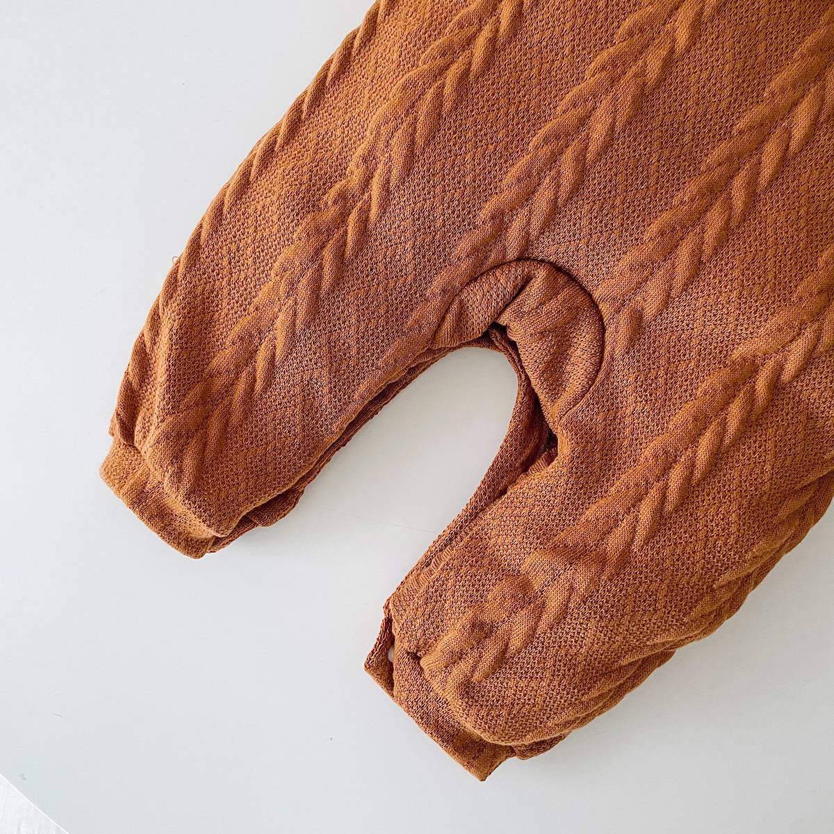 A cozy baby romper featuring a solid crochet-knitted pattern in white and brown, perfect for both baby girls and boys.