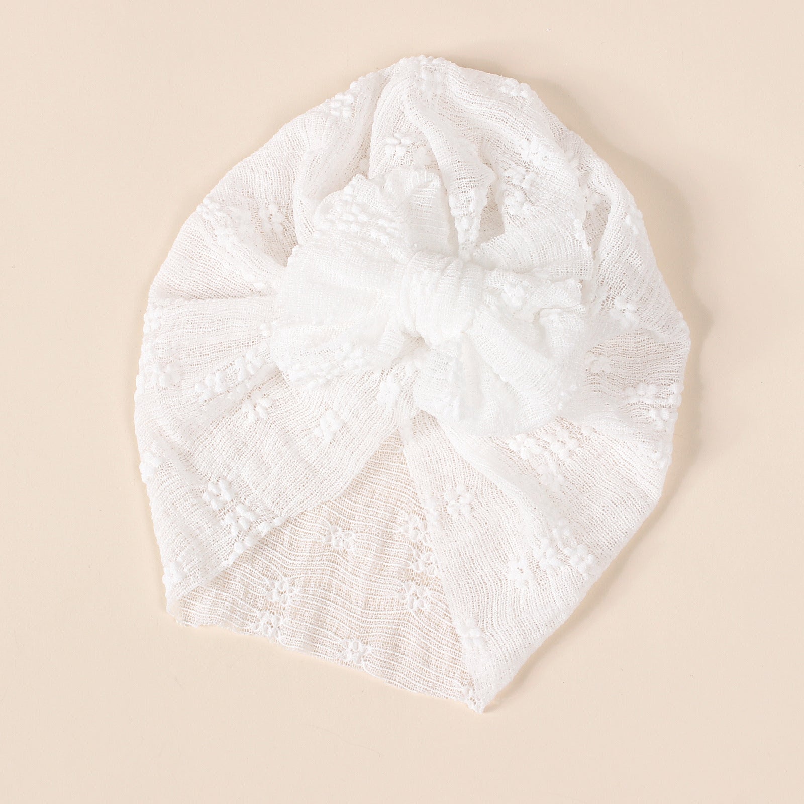 A collection of baby hats in solid colors including white, pink, blue, green, and beige, showcasing their elastic fit and breathable cotton material.