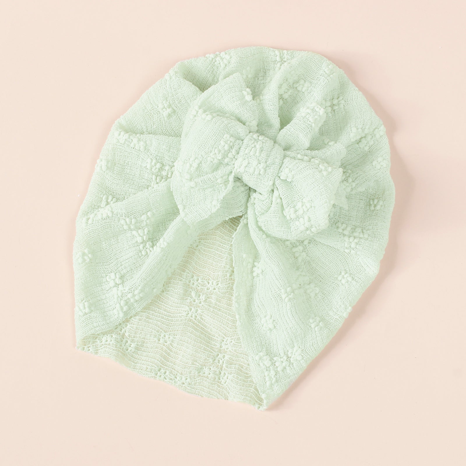 A collection of baby hats in solid colors including white, pink, blue, green, and beige, showcasing their elastic fit and breathable cotton material.