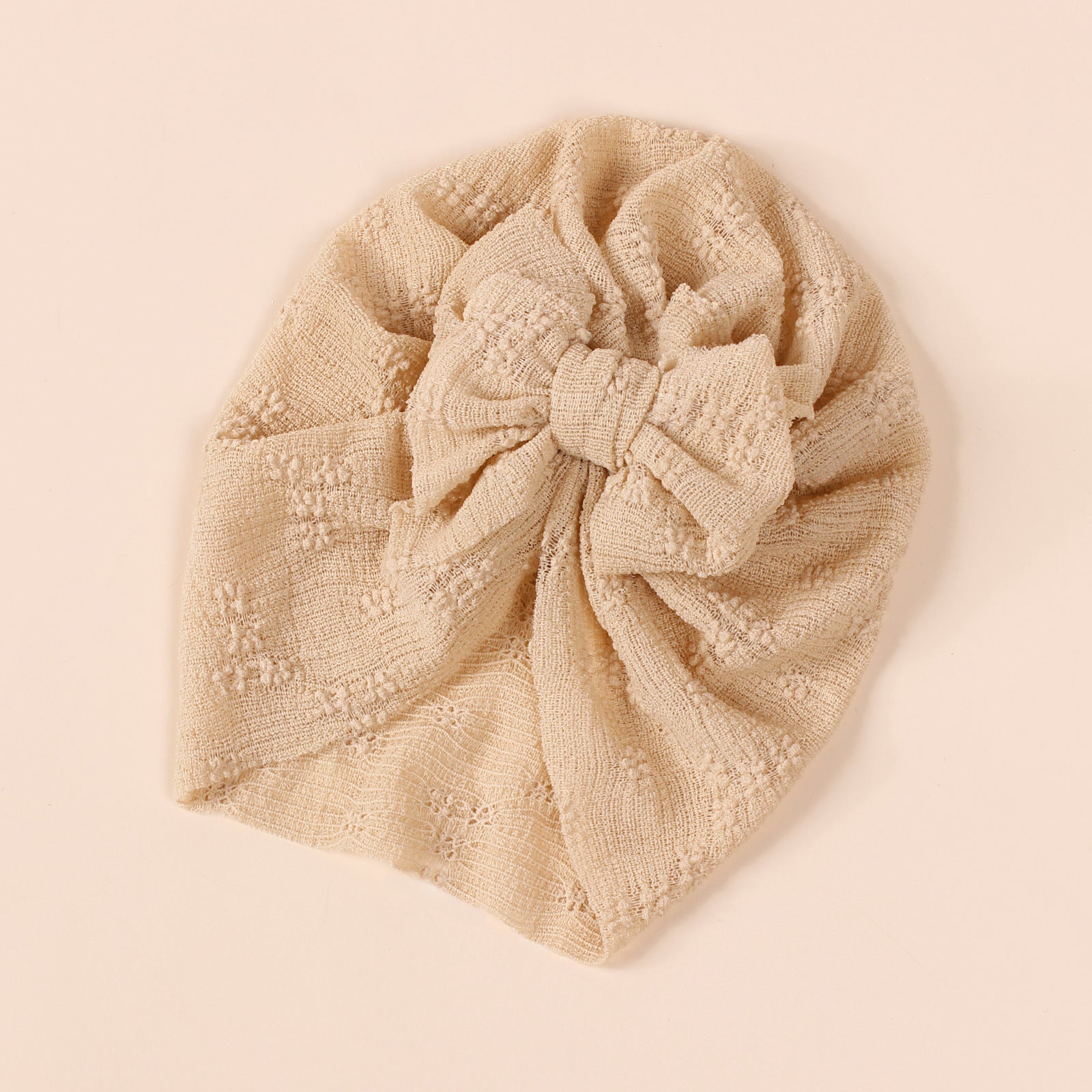 A collection of baby hats in solid colors including white, pink, blue, green, and beige, showcasing their elastic fit and breathable cotton material.