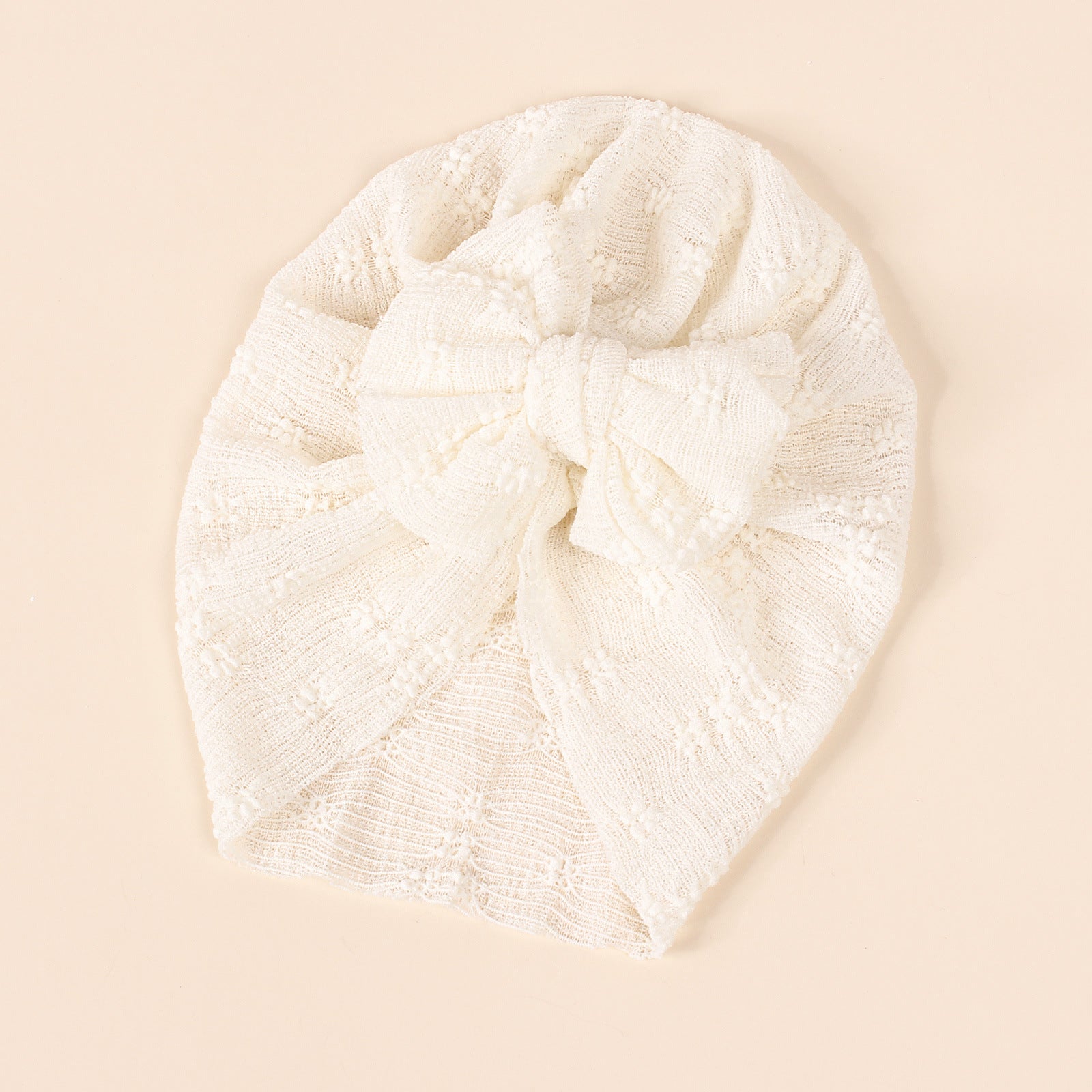 A collection of baby hats in solid colors including white, pink, blue, green, and beige, showcasing their elastic fit and breathable cotton material.