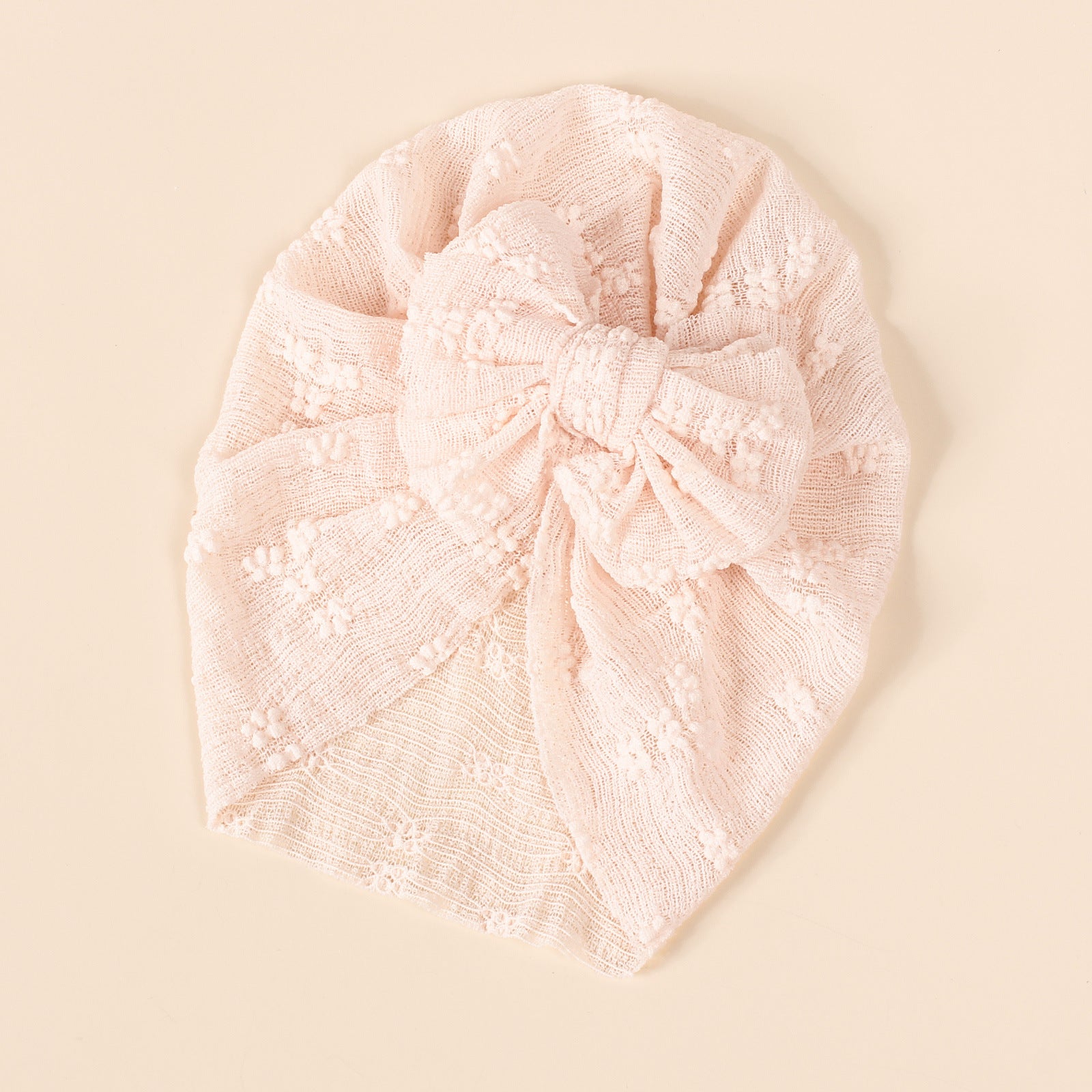 A collection of baby hats in solid colors including white, pink, blue, green, and beige, showcasing their elastic fit and breathable cotton material.