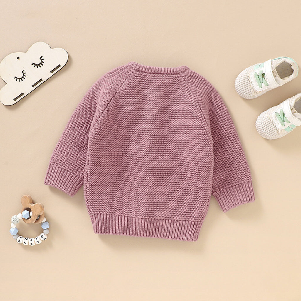 A beautifully handmade baby cardigan in solid colors, showcasing its long sleeves and soft cotton texture, perfect for infants.