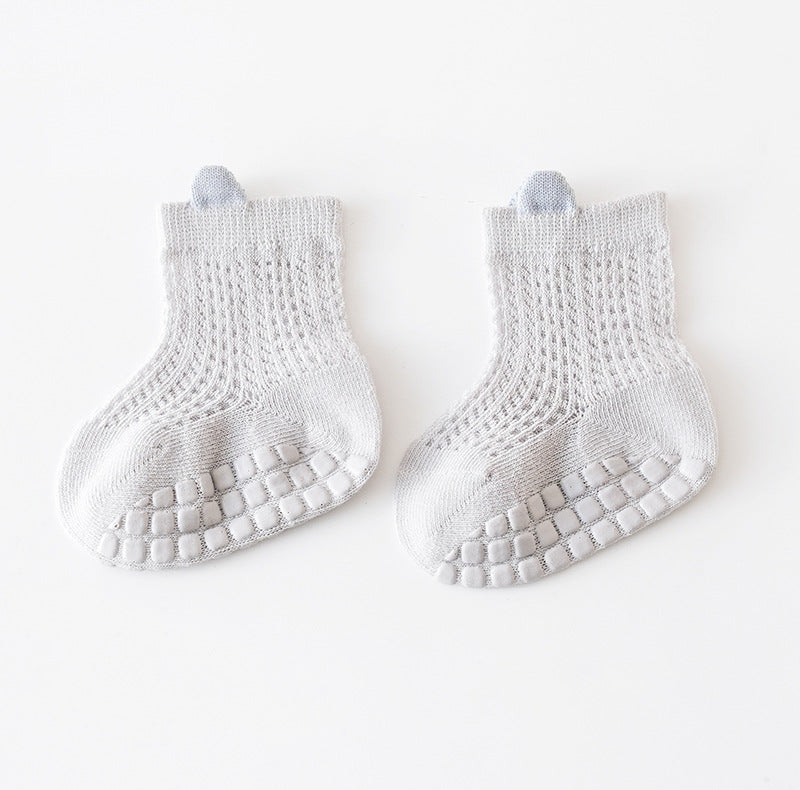 A pair of baby solid color non-slip toddler socks in a thin style, designed for summer with silicone grip bottoms for safety.