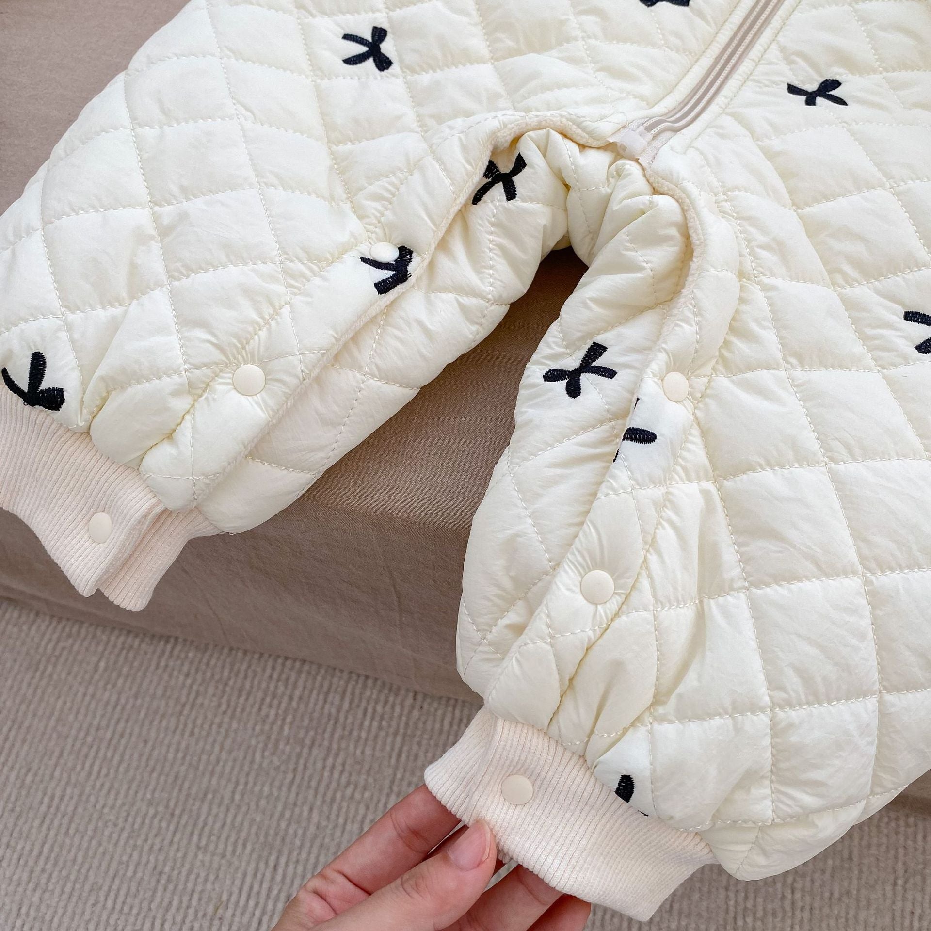 Baby toddler girl wearing a beige long sleeve outfit with bowknot design, perfect for winter.