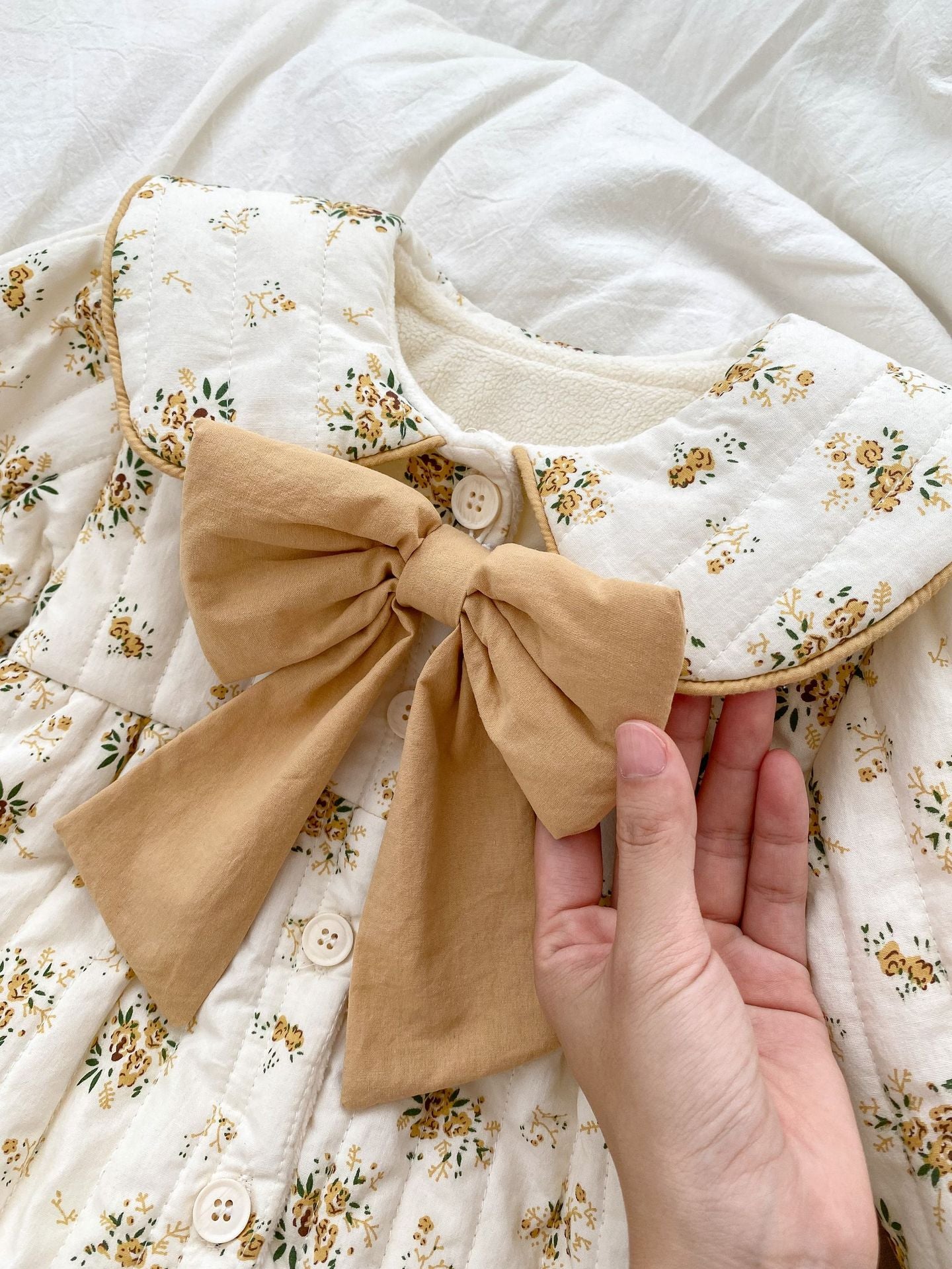 Baby toddler girl wearing a beige fleece floral print outfit with a big bow-knot and long sleeves, perfect for winter.