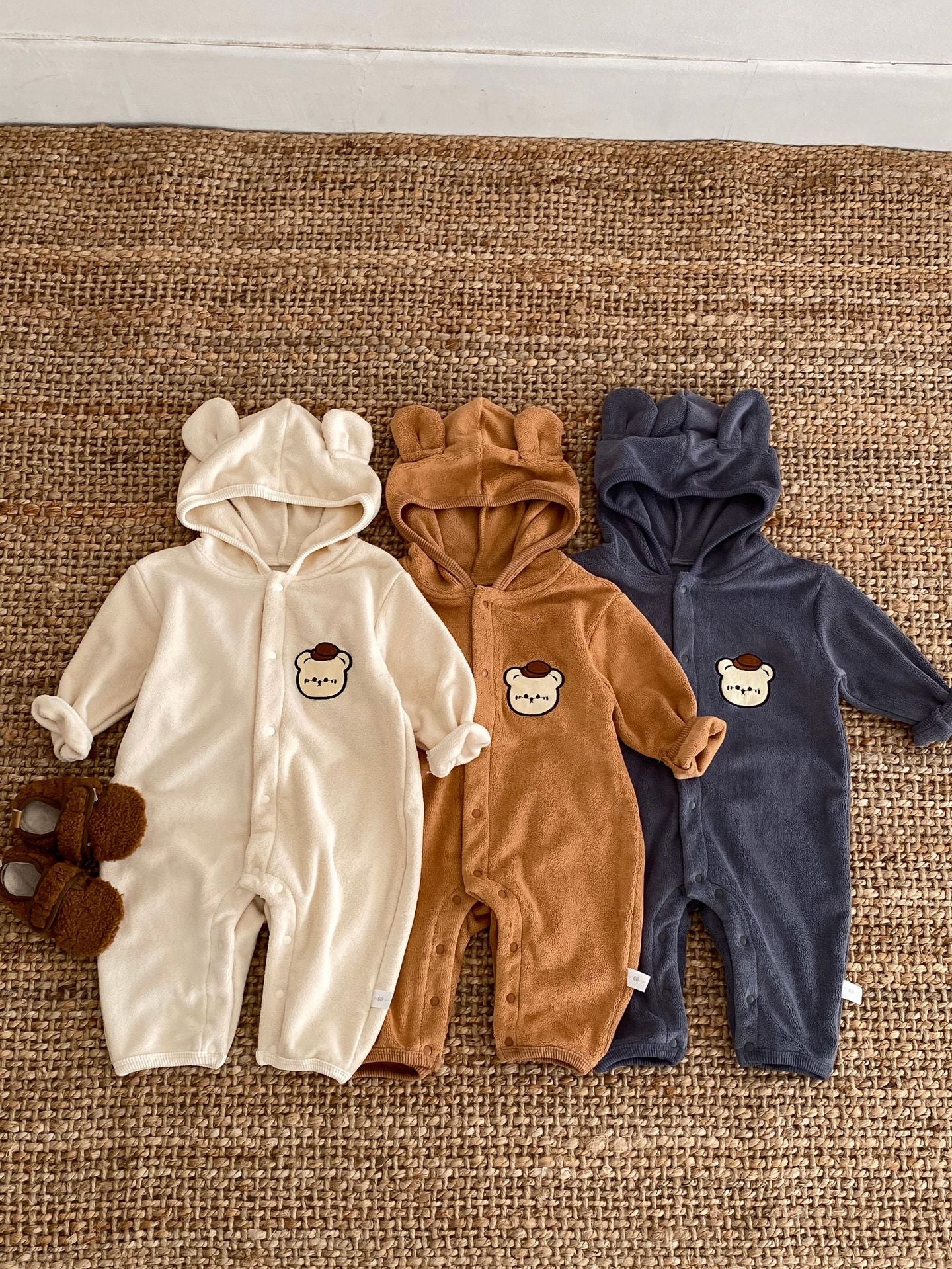 Baby unisex long sleeve romper featuring a cute bear head design, accompanied by a matching hat, available in navy blue, apricot, and brown.