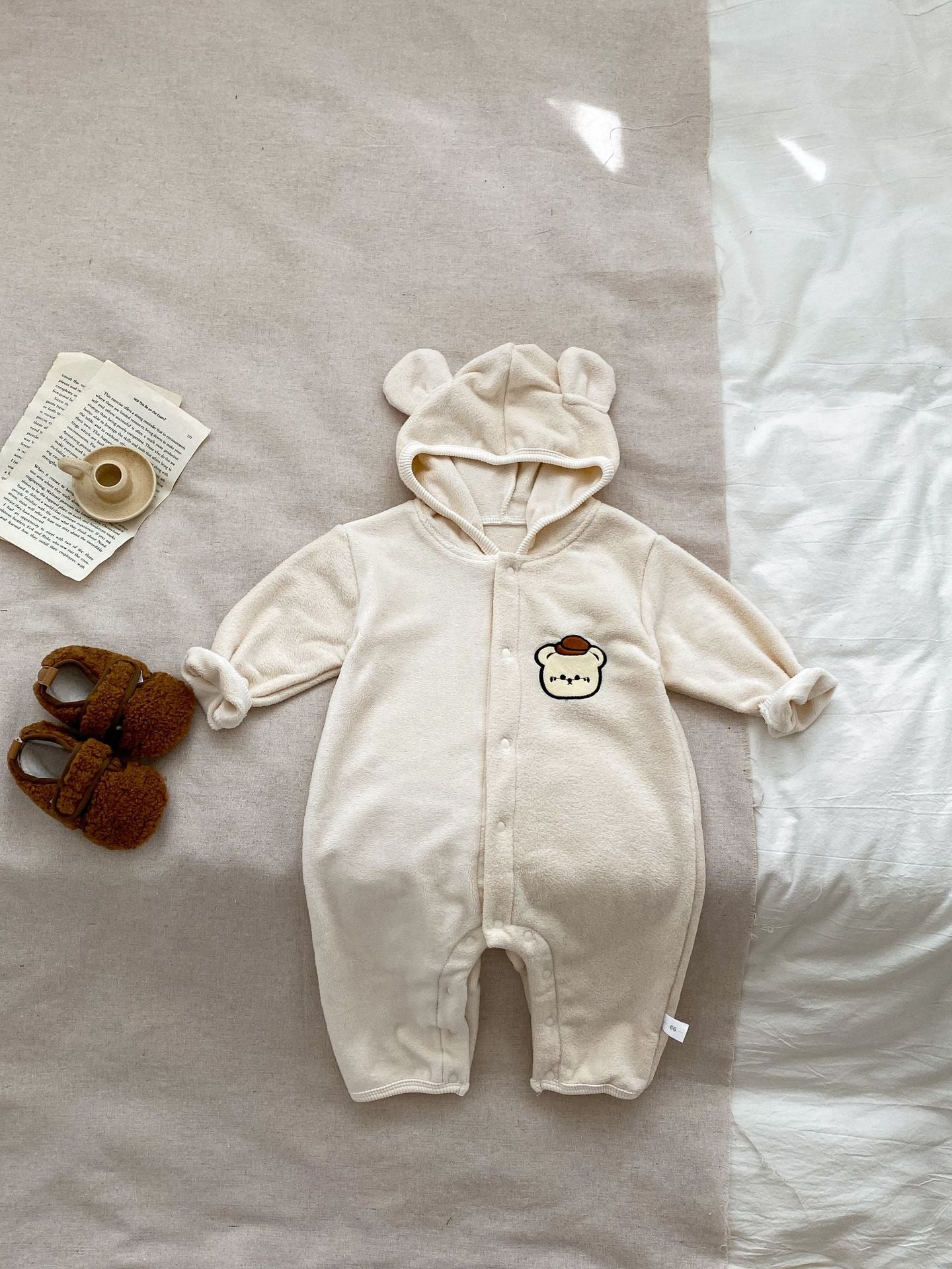 Baby unisex long sleeve romper featuring a cute bear head design, accompanied by a matching hat, available in navy blue, apricot, and brown.