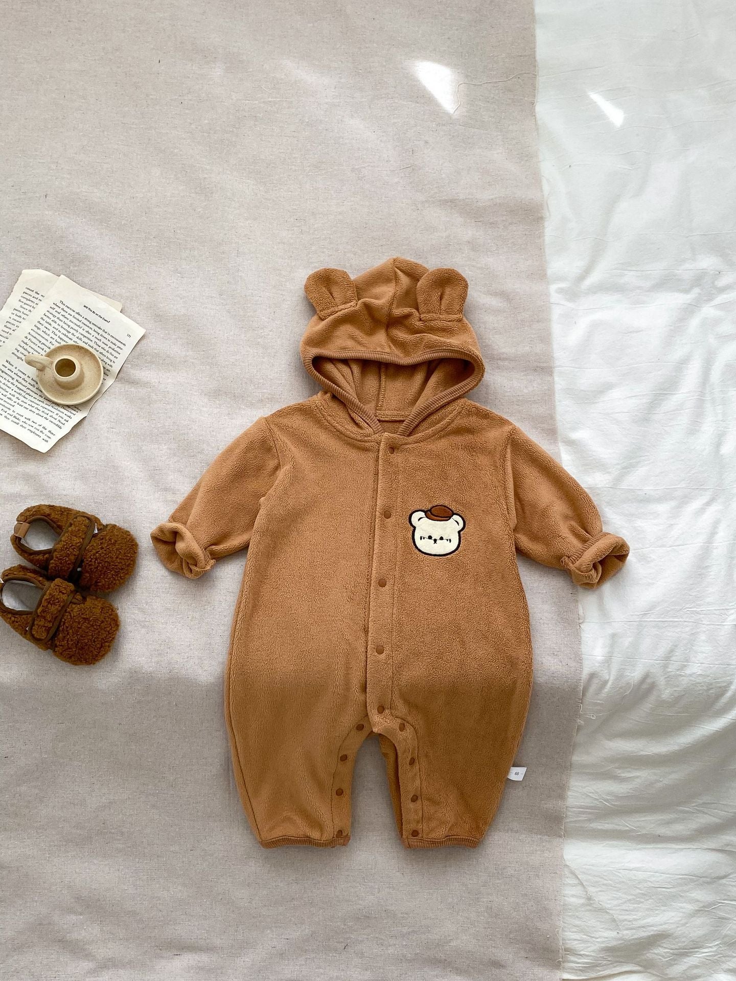 Baby unisex long sleeve romper featuring a cute bear head design, accompanied by a matching hat, available in navy blue, apricot, and brown.