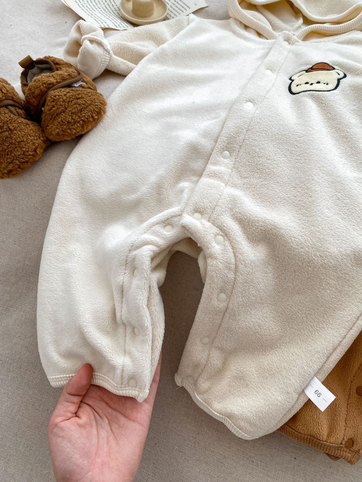Baby unisex long sleeve romper featuring a cute bear head design, accompanied by a matching hat, available in navy blue, apricot, and brown.