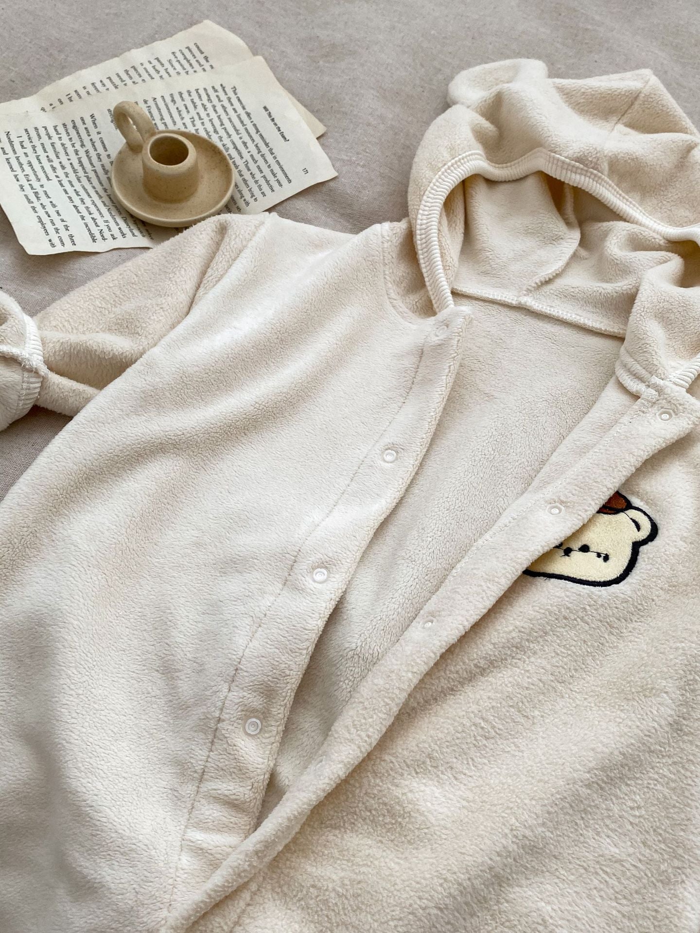 Baby unisex long sleeve romper featuring a cute bear head design, accompanied by a matching hat, available in navy blue, apricot, and brown.