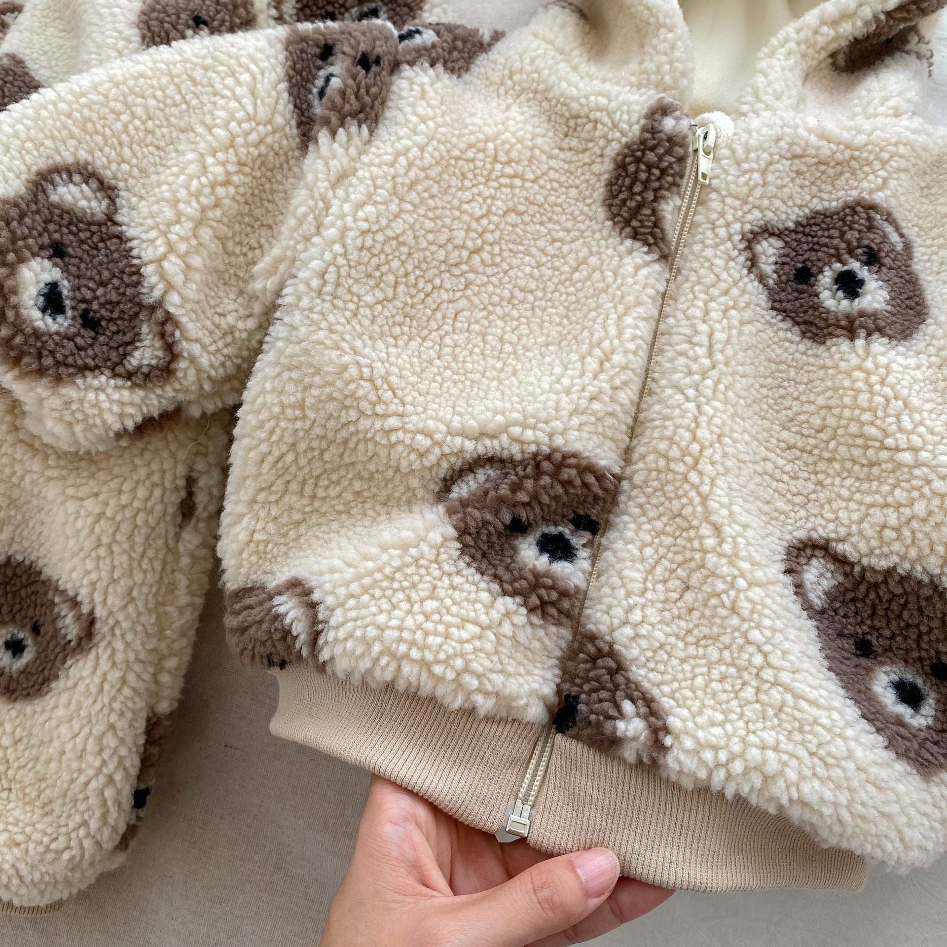 Baby wearing a warm plush coat with a bear head design, perfect for winter.