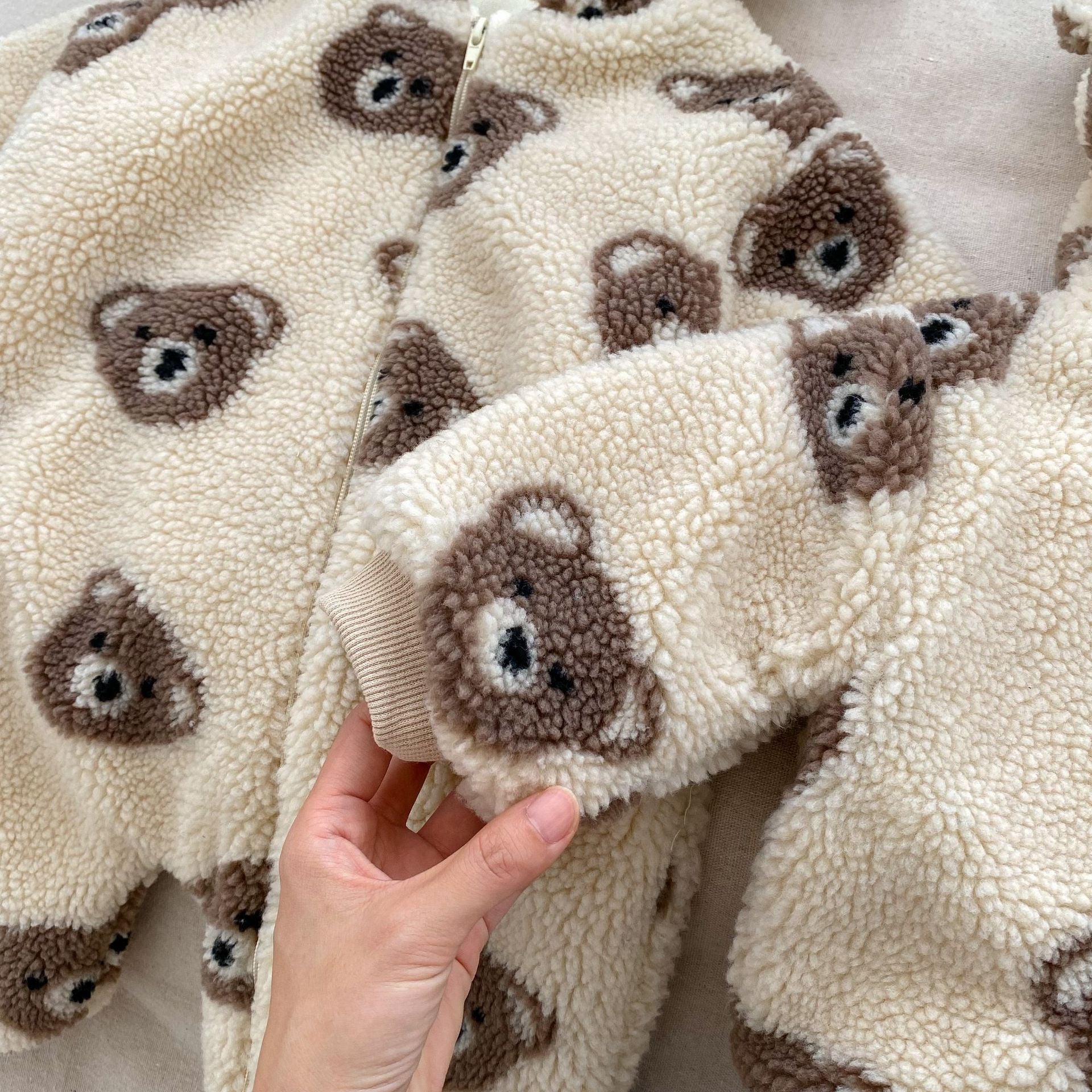Baby wearing a warm plush coat with a bear head design, perfect for winter.