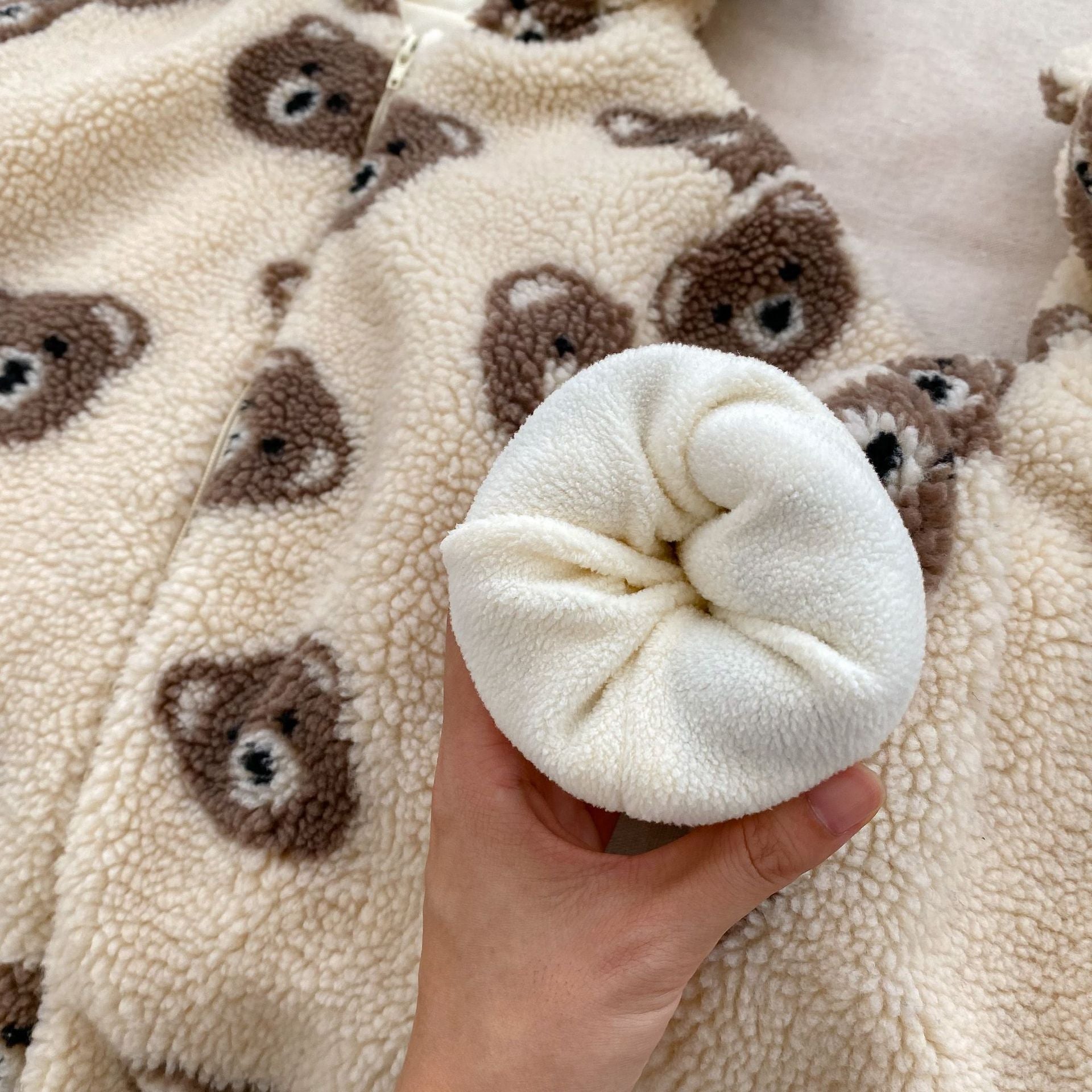 Baby wearing a warm plush coat with a bear head design, perfect for winter.