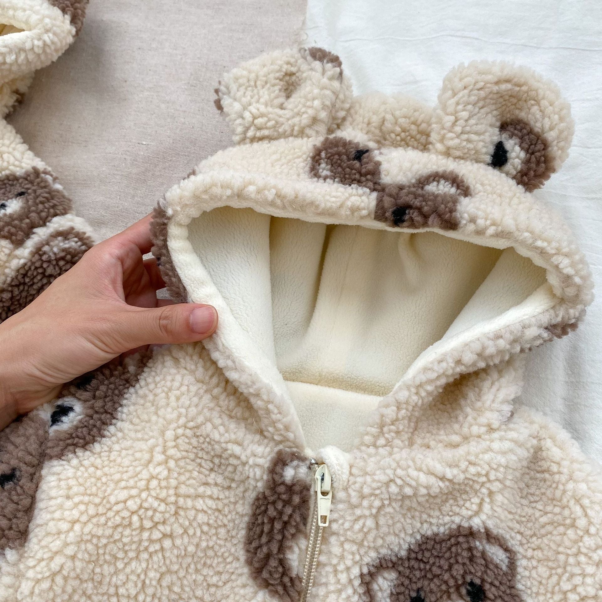Baby wearing a warm plush coat with a bear head design, perfect for winter.