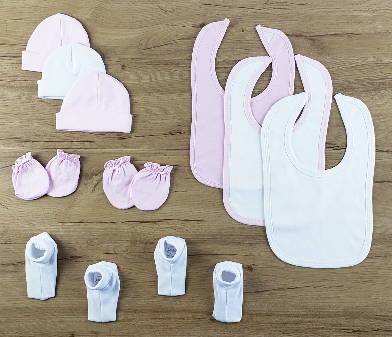 Bambini 10 PC set featuring soft cotton bibs, caps, and booties in pink and white, perfect for newborns.