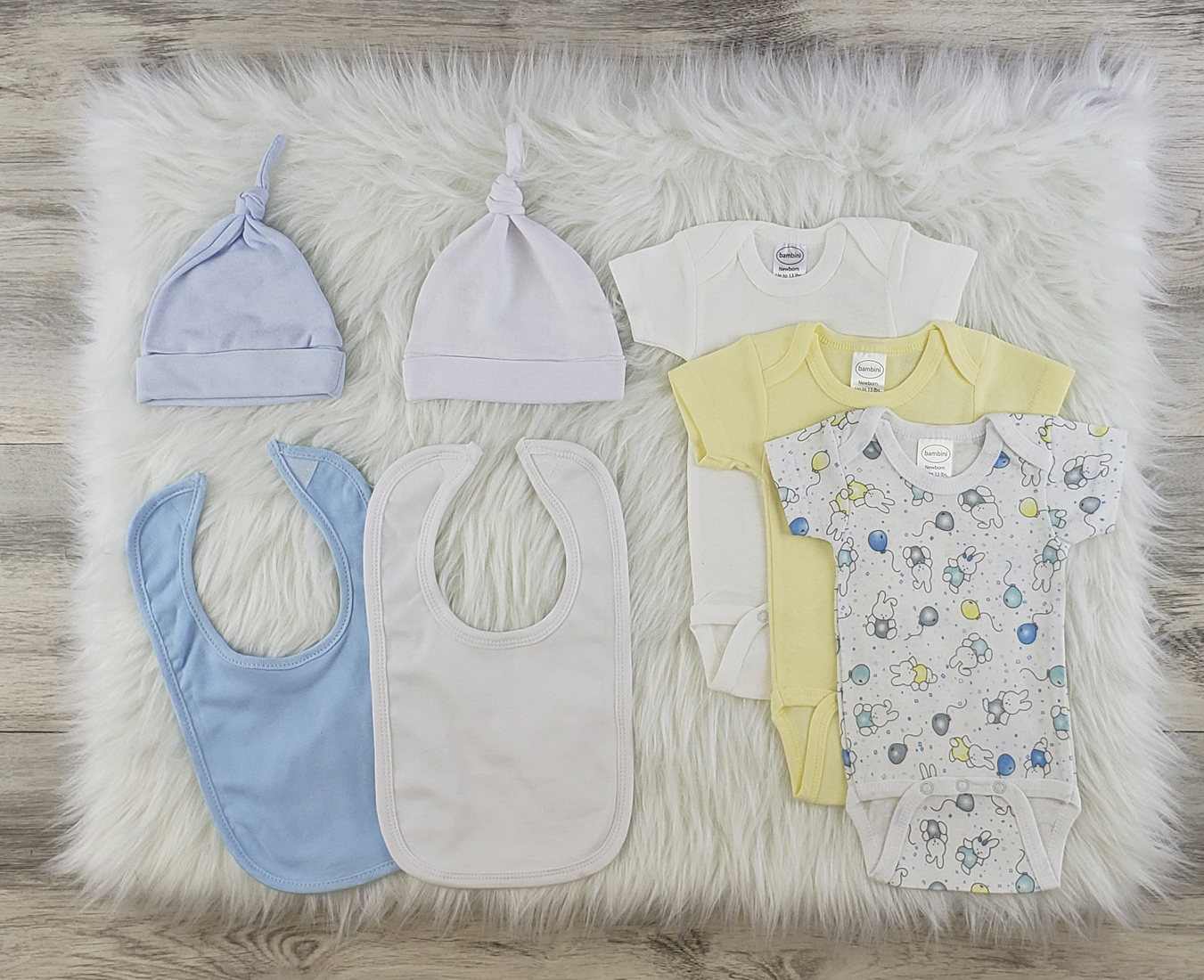 Bambini 7 Pc Layette Baby Clothes Set featuring soft cotton onesies, knotted caps, and interlock bibs in blue and white.