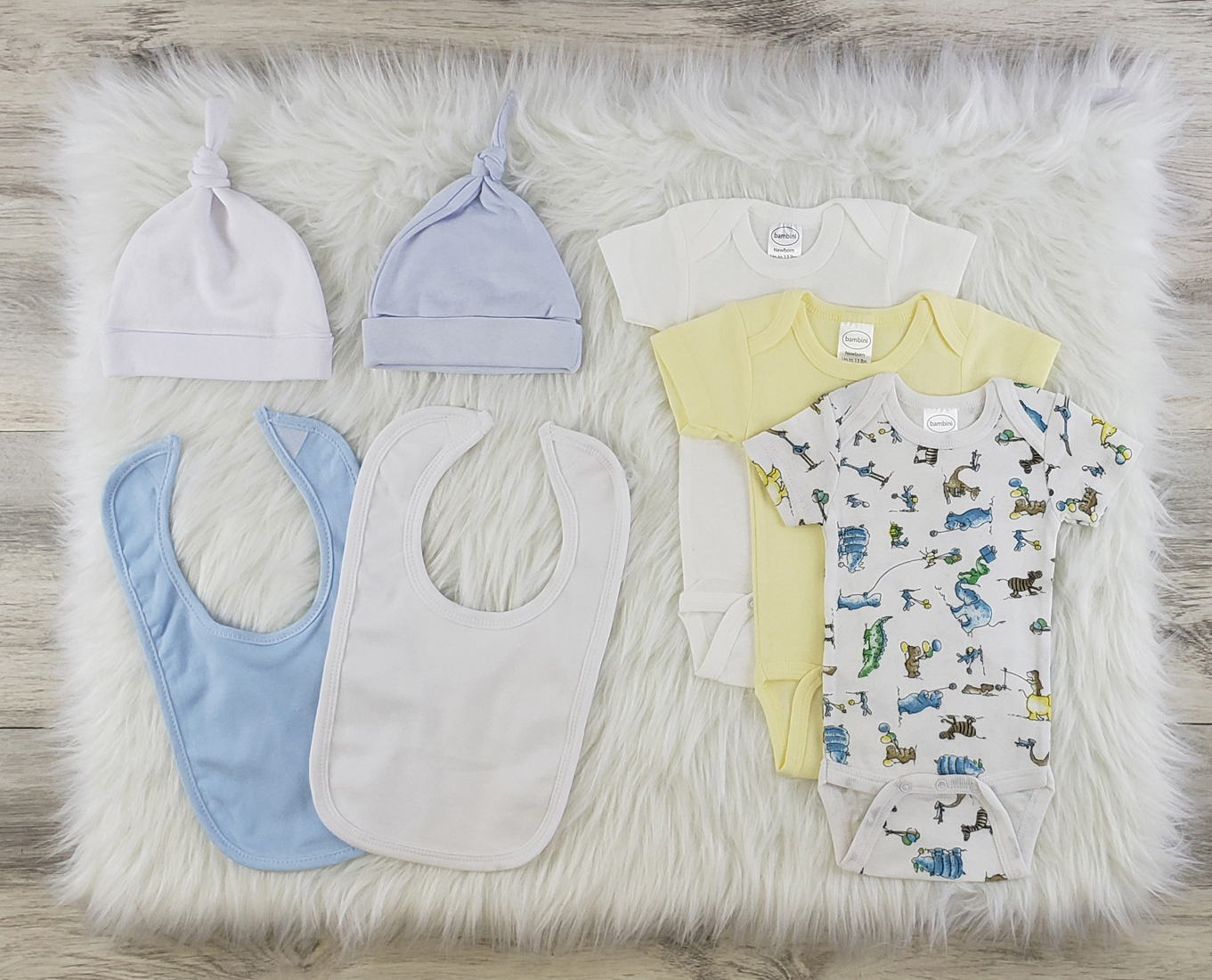 Bambini 7 Pc Layette Baby Clothes Set featuring soft cotton onesies, knotted caps, and bibs in blue and white, perfect for newborns.