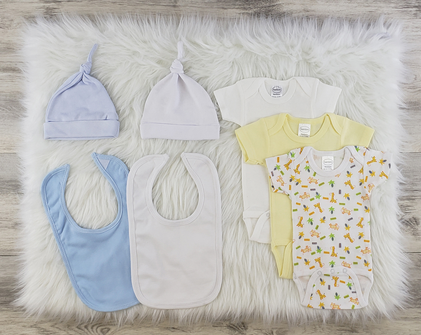 Bambini 7 Pc Layette Baby Clothes Set featuring soft cotton onesies, knotted caps, and interlock bibs in blue and white.