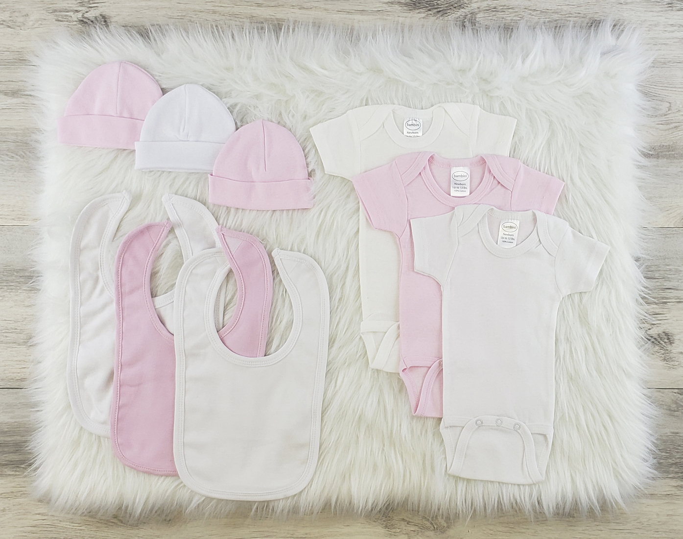 Bambini 9 Pc Layette Baby Clothes Set featuring soft cotton onesies, caps, and bibs in pink and white, perfect for newborns.