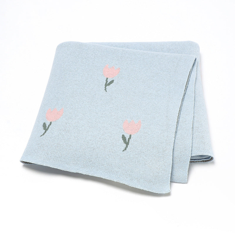 A beautifully knitted baby blanket featuring a fresh floral design in soft cotton, available in multiple colors including pink and blue.