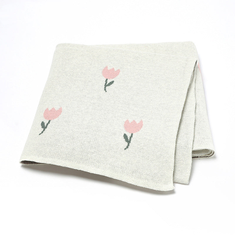 A beautifully knitted baby blanket featuring a fresh floral design in soft cotton, available in multiple colors including pink and blue.