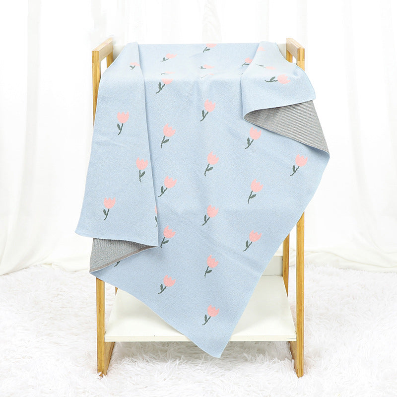 A beautifully knitted baby blanket featuring a fresh floral design in soft cotton, available in multiple colors including pink and blue.