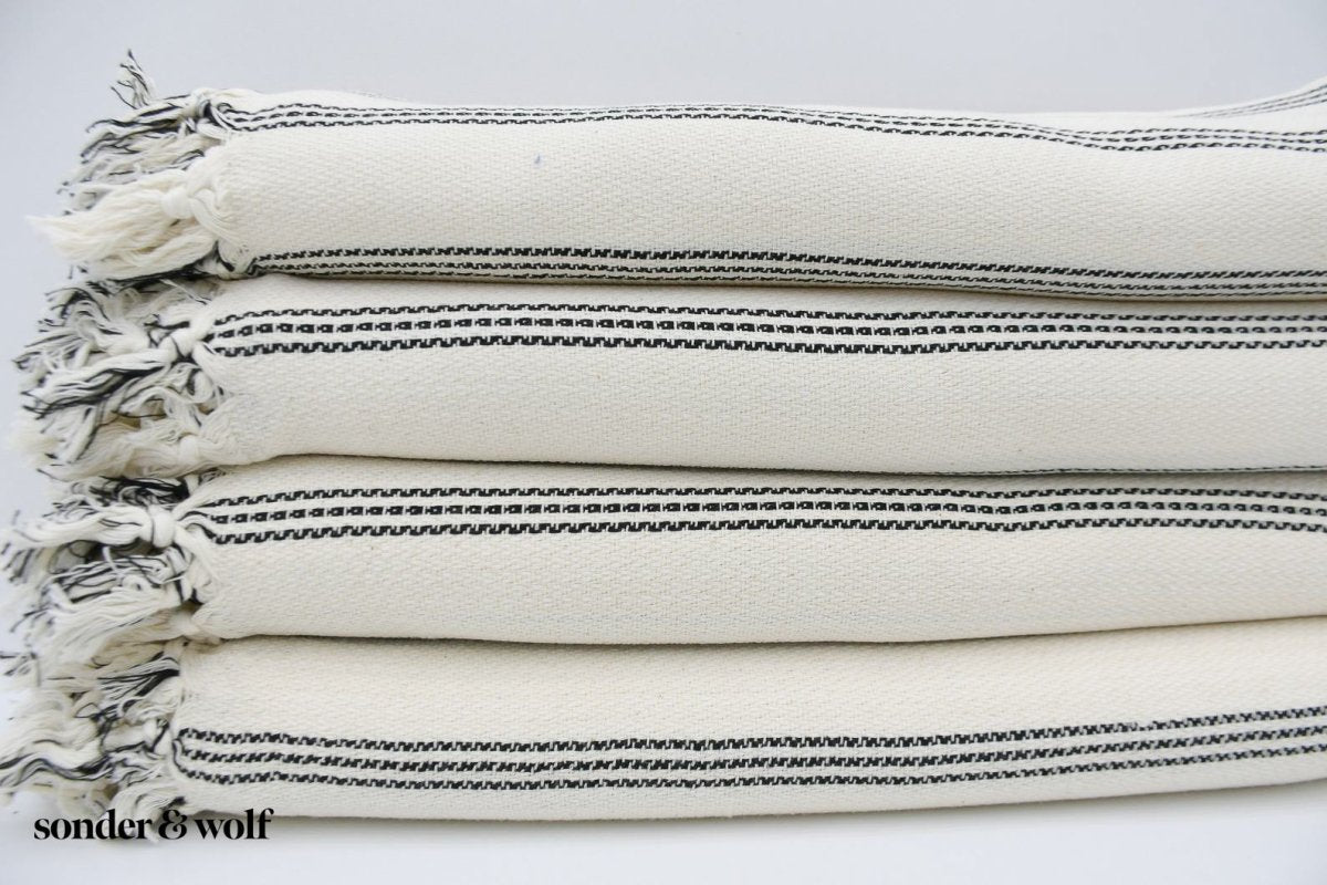 Black and white striped Turkish beach towel, lightweight and stylish, perfect for beach outings and versatile uses.