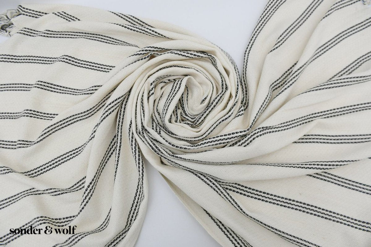 Black and white striped Turkish beach towel, lightweight and stylish, perfect for beach outings and versatile uses.
