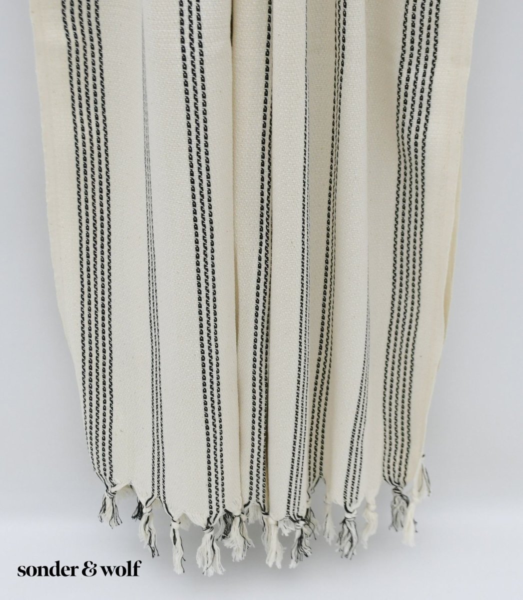Black and white striped Turkish beach towel, lightweight and stylish, perfect for beach outings and versatile uses.