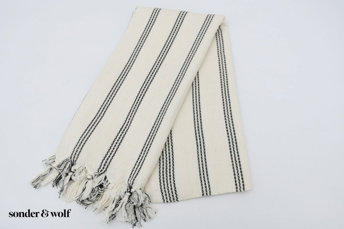 Black and white striped Turkish beach towel, lightweight and stylish, perfect for beach outings and versatile uses.