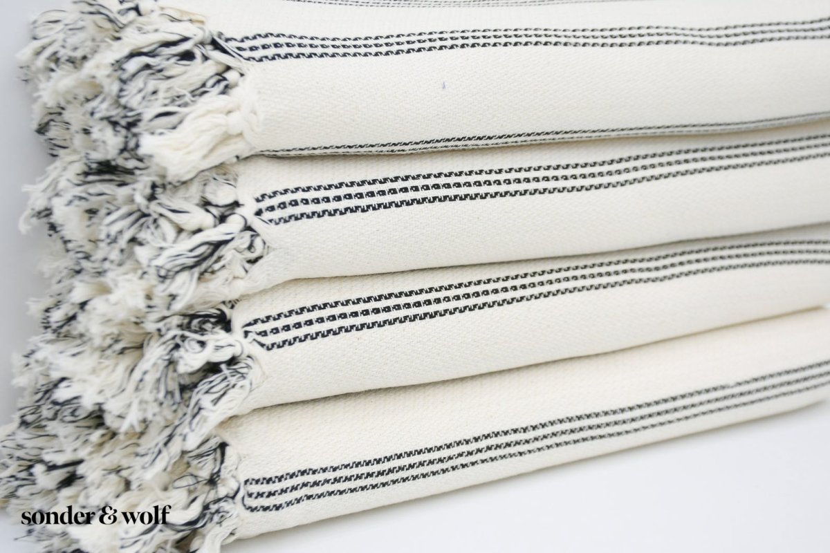 Black and white striped Turkish beach towel, lightweight and stylish, perfect for beach outings and versatile uses.