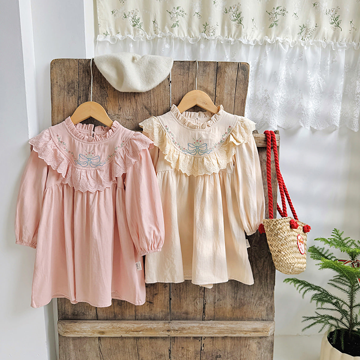 A beautiful long dress for girls featuring floral and bow embroidery, ruffle neck design, available in pink and beige colors.