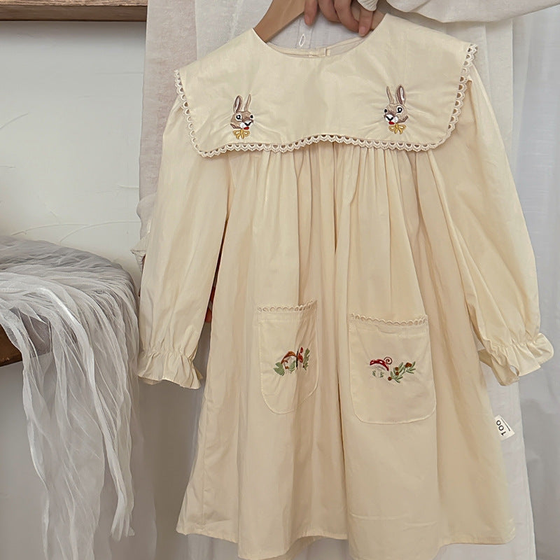A long dress featuring an embroidered design of rabbits and mushrooms in pink and beige colors, perfect for autumn wear for girls.