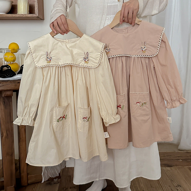 A long dress featuring an embroidered design of rabbits and mushrooms in pink and beige colors, perfect for autumn wear for girls.