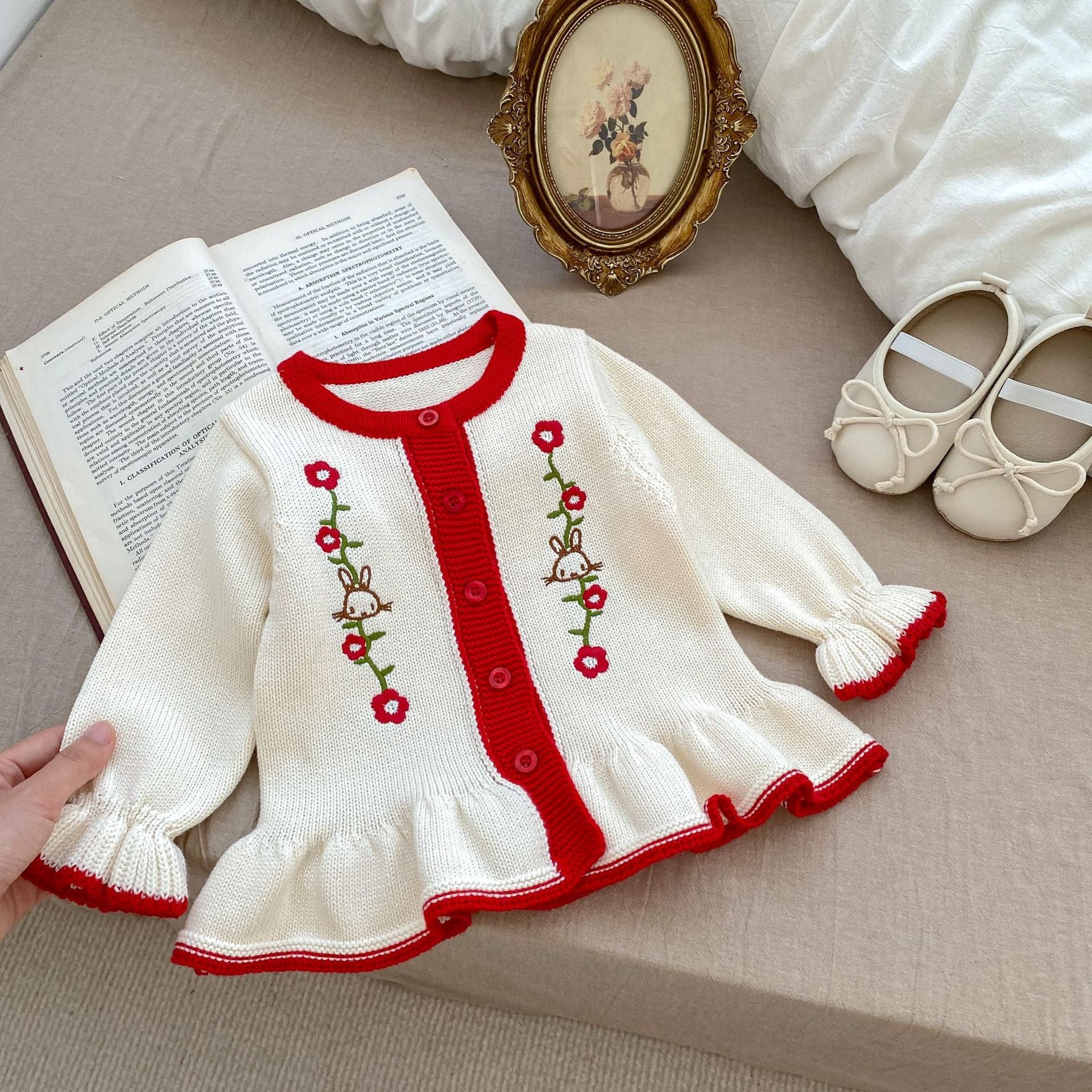 A beige knitted cardigan for baby girls featuring floral embroidery, perfect for autumn wear.