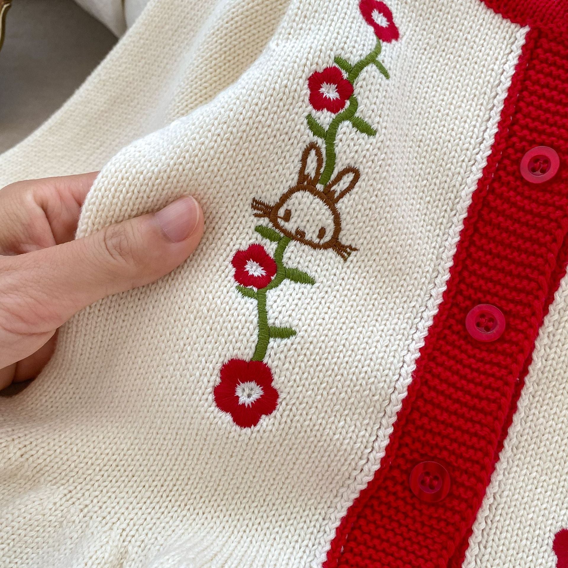 A beige knitted cardigan for baby girls featuring floral embroidery, perfect for autumn wear.