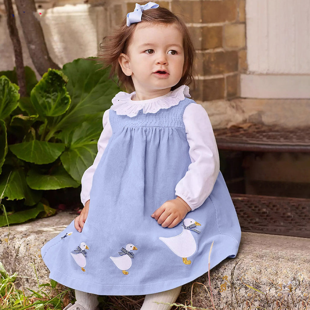 A vibrant sleeveless dress for girls featuring cartoon graphics in pink and blue colors, made from soft cotton fabric.