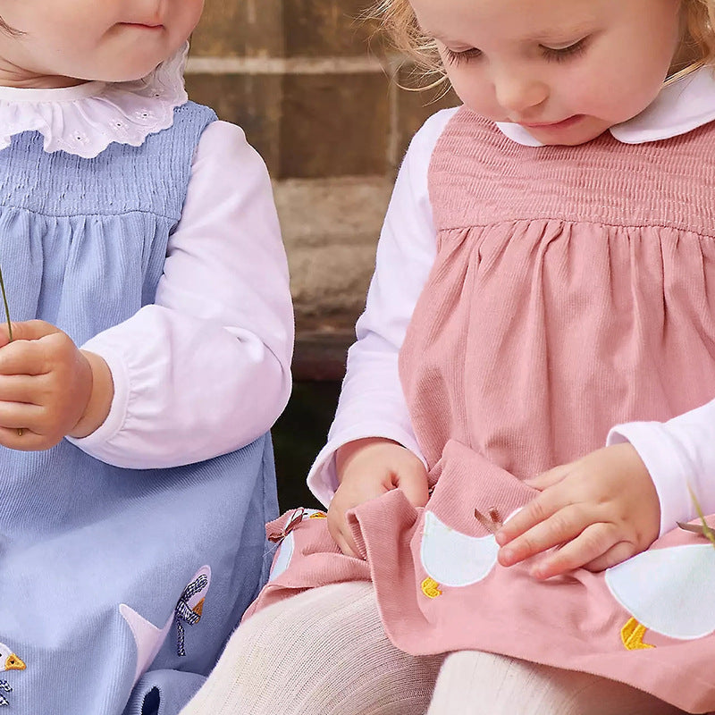 A vibrant sleeveless dress for girls featuring cartoon graphics in pink and blue colors, made from soft cotton fabric.