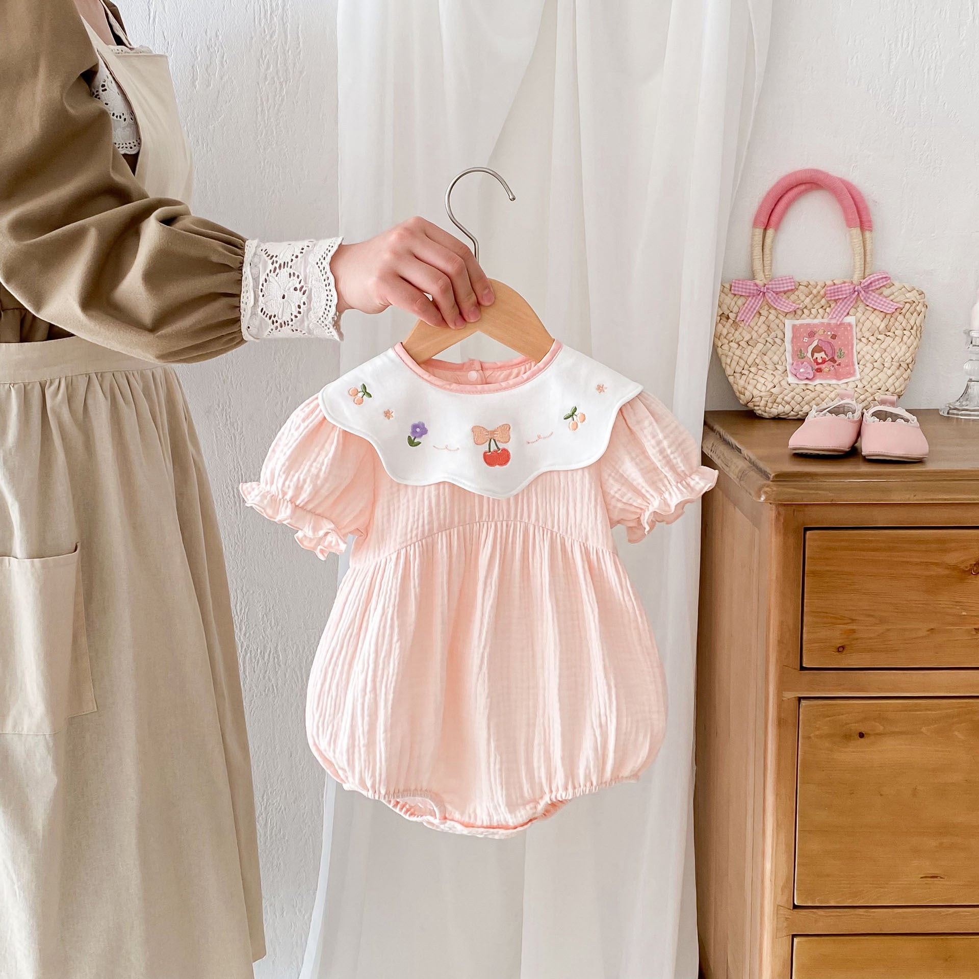 A cute pink short-sleeved summer outfit for baby girls featuring embroidered fruits, perfect for warm weather.