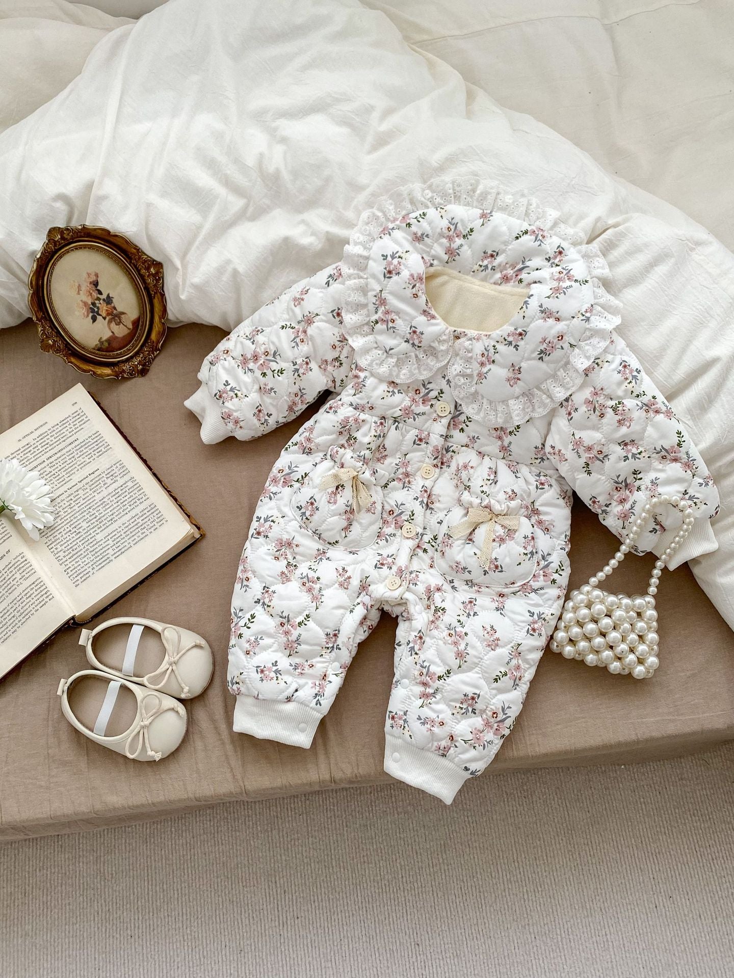 Infant baby girl wearing a floral long sleeve jumpsuit with laces, perfect for winter.