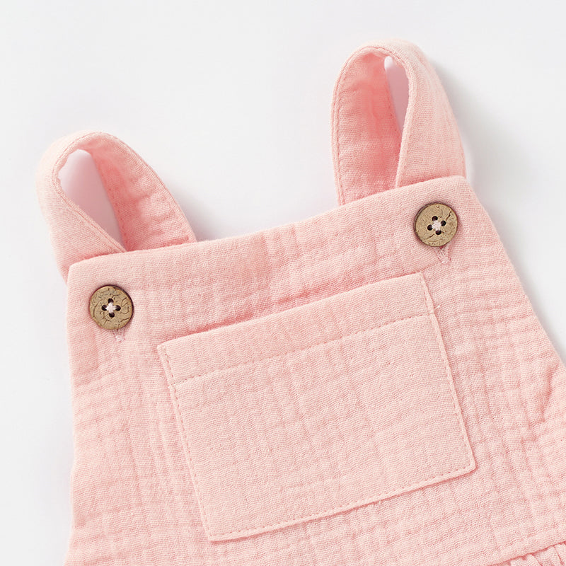 A soft and stylish Organic Cotton Muslin Baby Dress in three colors, featuring button straps and textured fabric, perfect for babies.